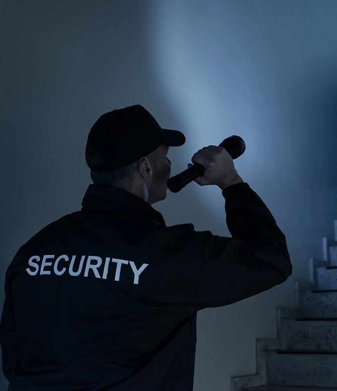 Male-security-guard-looking-around-office-building-at-night